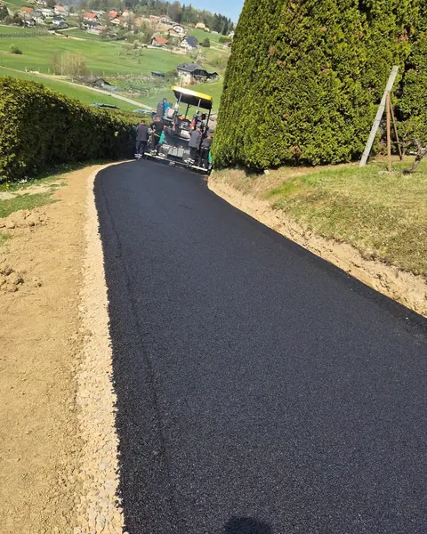Sveže asfaltirana dovozna pot ob živi meji