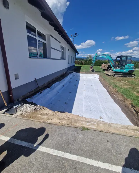 Geotekstil v izkopu ob objektu, v ozadju bagra