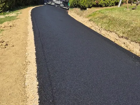 Sveže asfaltirana dovozna pot ob živi meji